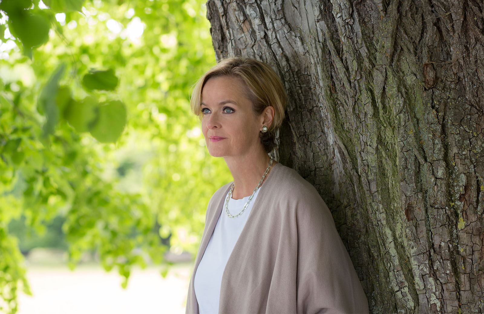 Uschi Lauterbach Coaching – Frau lehnt an Baum unter Blätterdach